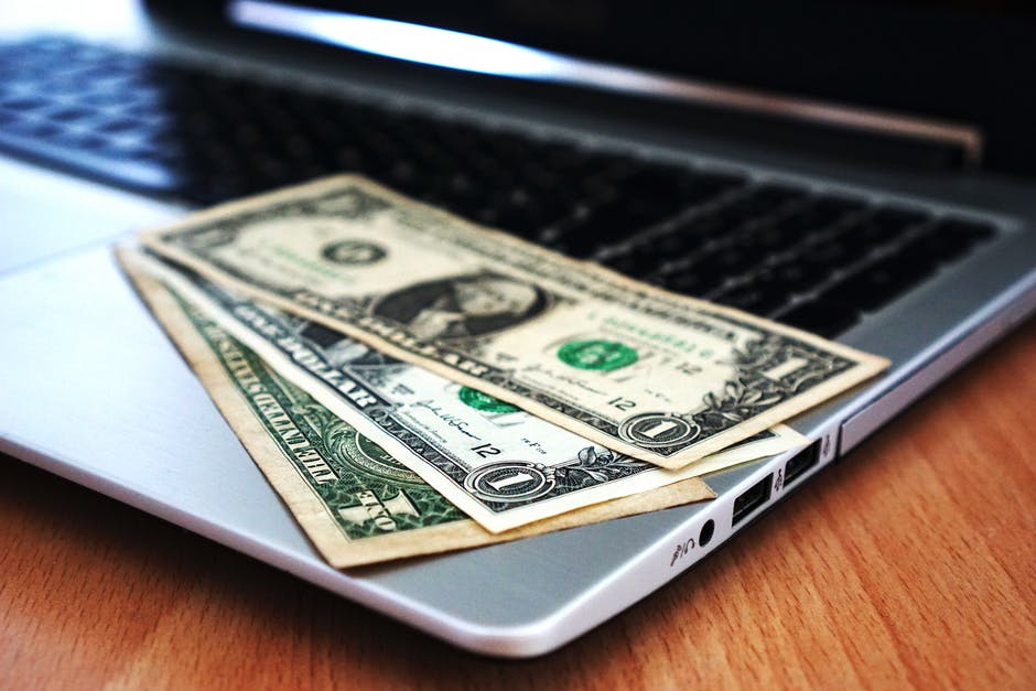 Stock photo of dollar bills laying on top of a laptop.